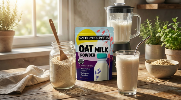 Wilderness Poets Oat milk powder packaging with a jar of oat flour, a glass of oat milk, and a blender on a wooden table.